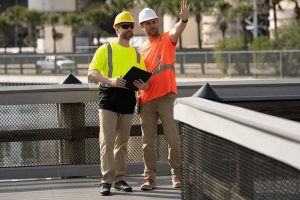 Two construction workers in hard hats reviewing documents on Florida job site - workers comp insurance