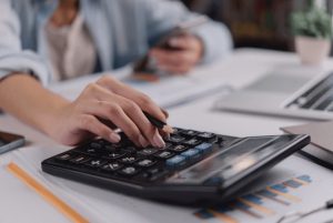 Woman using calculator reviewing financial documents - payroll outsourcing small business