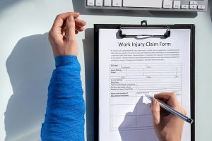 Worker filling out injury claim form on clipboard - workers comp claims Florida